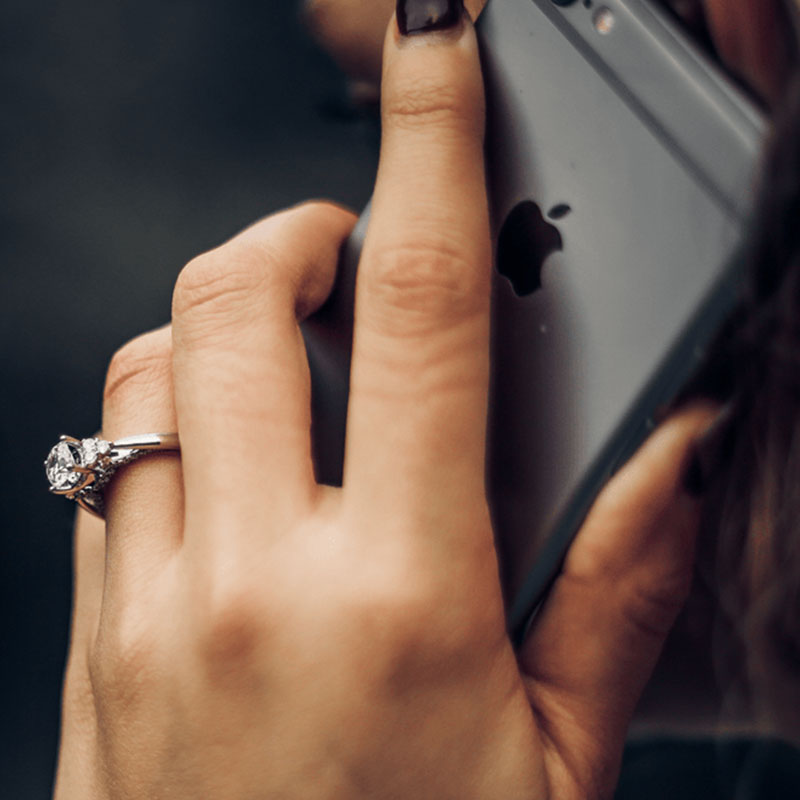 close up of a woman's hand showing an engagement ring making a call on an iPhone