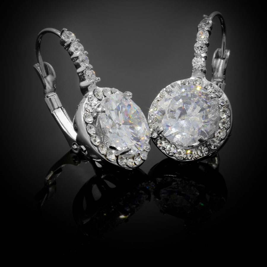 Earrings A pair of diamond earrings showing highlights on the large center stones on a dark background with a reflected surface.