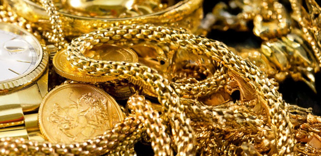 Gold jewelry sitting on hundreds of dollar bills.