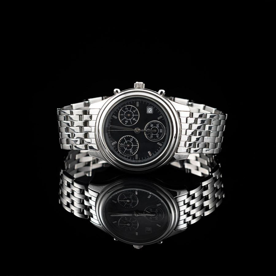 Watches A gents white metal watch with a black face on a black background reflecting