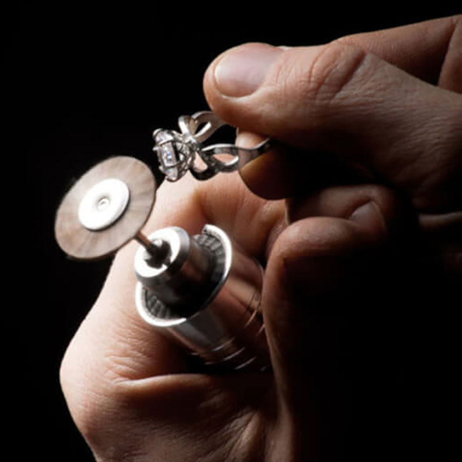 closeup of the jeweler's hands polishing the engagement ring's diamond