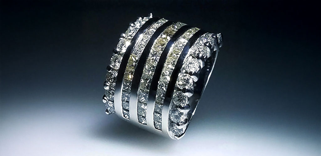 Custom designed diamond engagement ring with a heart shaped center stone and round diamonds on the band. Isolated on a black background.